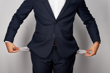 young businessman showing empty pockets, studio shot, isolated on white background