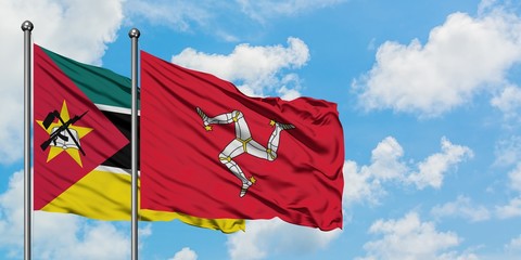 Mozambique and Isle Of Man flag waving in the wind against white cloudy blue sky together. Diplomacy concept, international relations.
