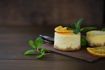 Cheesecake with slices of orange and mint on a wooden background. Top view.