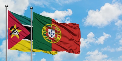Mozambique and Portugal flag waving in the wind against white cloudy blue sky together. Diplomacy concept, international relations.