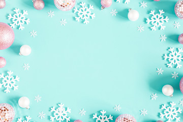 Christmas composition. Frame made of pink balls and white snowflakes on pastel blue background. Christmas, winter, new year concept. Flat lay, top view, copy space