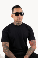 Tattooed man sitting wearing black t-shirt and sunglasses