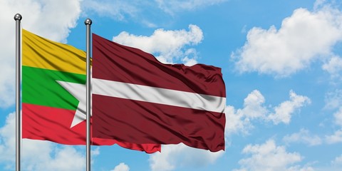 Myanmar and Latvia flag waving in the wind against white cloudy blue sky together. Diplomacy concept, international relations.