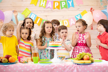 Group of preschool children gathered around birthday cake with candles