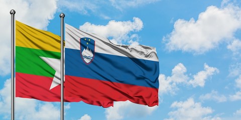 Myanmar and Slovenia flag waving in the wind against white cloudy blue sky together. Diplomacy concept, international relations.