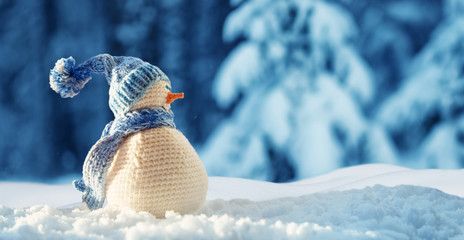 little snowman on soft snow on blue background