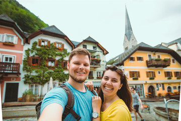 Fototapeta na wymiar smiling lovely couple taking selfie at hallstatt city central square