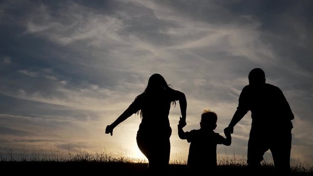 happy family funny go for are running a teamwork Silhouette, happy children with mother and father, family at sunset. mom dad and son stand walking runners on the edge of a cliff of a hill watching