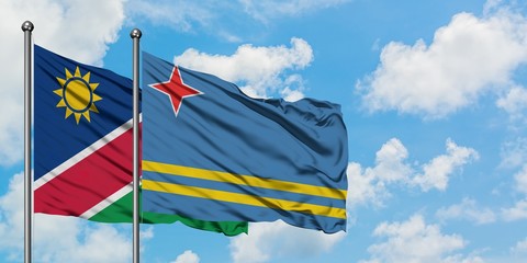 Namibia and Aruba flag waving in the wind against white cloudy blue sky together. Diplomacy concept, international relations.