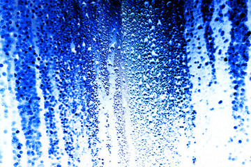 Naklejka na ściany i meble Drops on glass on a blue background
