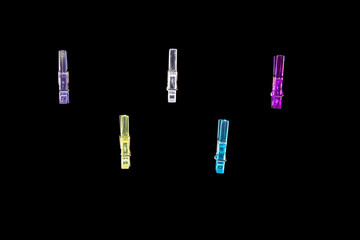  Mini colorful clothespins, arranged in staggered rows, on a black background