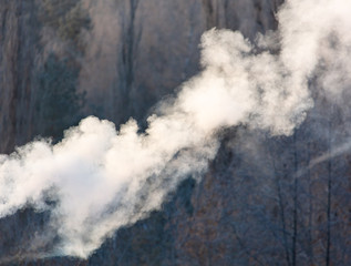 Smoke from the chimney of a house at dawn of the sun