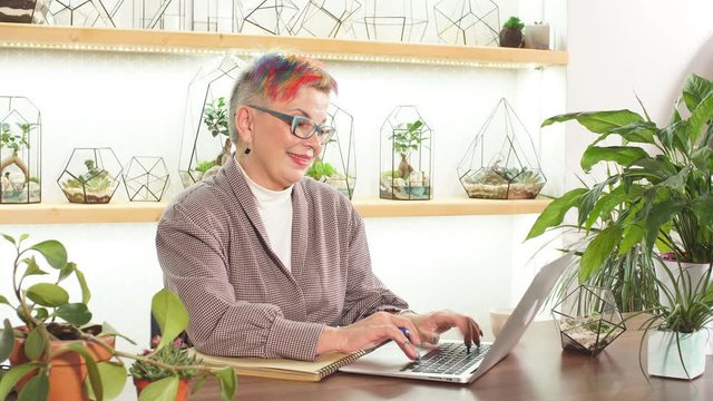 Portrait of open-minded business lady with glasses smile while sitting on table with notebooks and laptop, look at camera. Business people concept