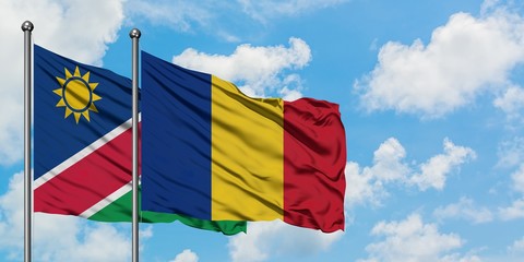 Namibia and Romania flag waving in the wind against white cloudy blue sky together. Diplomacy concept, international relations.