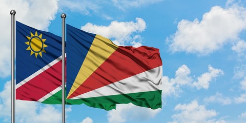 Namibia and Seychelles flag waving in the wind against white cloudy blue sky together. Diplomacy concept, international relations.