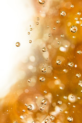 Bubbles of air on the smooth surface of golden water as an abstract background