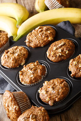 Healthy breakfast banana walnut muffins close-up in a baking dish on the table. vertical