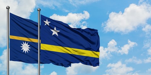 Nauru and Curacao flag waving in the wind against white cloudy blue sky together. Diplomacy concept, international relations.
