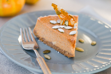 Pumpkin pie with caramel  on decorative plate. Whole pie in soft focus in background. Macro with shallow dof