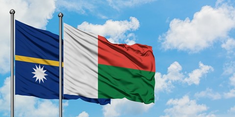 Nauru and Madagascar flag waving in the wind against white cloudy blue sky together. Diplomacy concept, international relations.