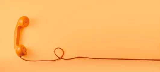 Fotobehang Een oranje vintage telefoontoestel met oranje achtergrond. © maramade