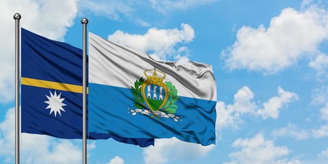 Nauru and San Marino flag waving in the wind against white cloudy blue sky together. Diplomacy...