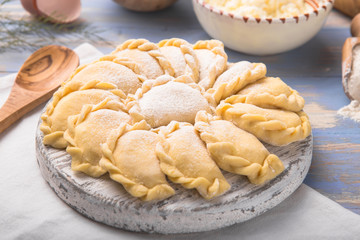 Raw dumplings, pierogi or pyrohy, varenyky, vareniki, served with cottage cheese on board. National Russian cuisine, natural organic homemade bakery product, view from above.