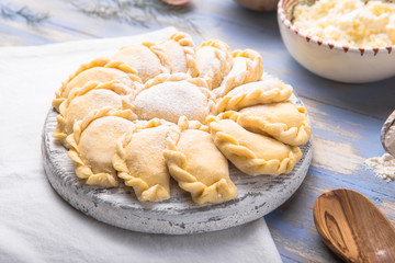 Raw dumplings, pierogi or pyrohy, varenyky, vareniki, served with cottage cheese on board. National Russian cuisine, natural organic homemade bakery product, view from above.