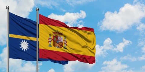 Nauru and Spain flag waving in the wind against white cloudy blue sky together. Diplomacy concept, international relations.