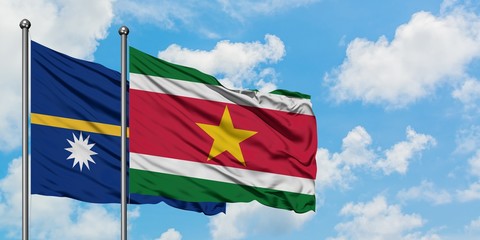 Nauru and Suriname flag waving in the wind against white cloudy blue sky together. Diplomacy concept, international relations.