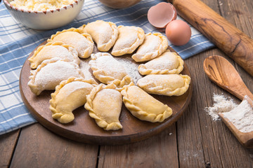 Raw dumplings, pierogi or pyrohy, varenyky, vareniki, served with cottage cheese on board. National Russian cuisine, natural organic homemade bakery product, view from above.