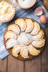 Raw dumplings, pierogi or pyrohy, varenyky, vareniki, served with cottage cheese on board. National Russian cuisine, natural organic homemade bakery product, view from above.