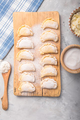 Raw dumplings, pierogi or pyrohy, varenyky, vareniki, served with cottage cheese on board. National Russian cuisine, natural organic homemade bakery product, view from above.