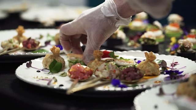 Catering company preparing large numbers of food beautifully decorating it, delicious gourmet meal is being given the finishing touches by the chef in a restaurant.