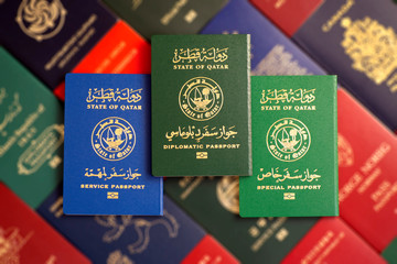 Various Qatar state passports on a blurred background of passports of the countries of the world.