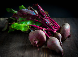 Raw beetroot with green leaves on a wooden table dark mood photo