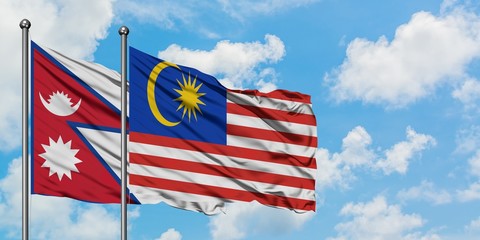 Nepal and Malaysia flag waving in the wind against white cloudy blue sky together. Diplomacy concept, international relations.