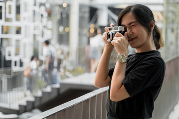 Happy asian woman taking photograph with camera in the city