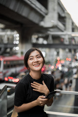 Happy asian woman looking at her phone in the city