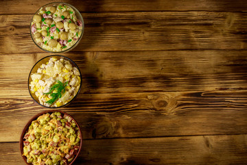 Set of festive mayonnaise salads on wooden table. Top view, copy space