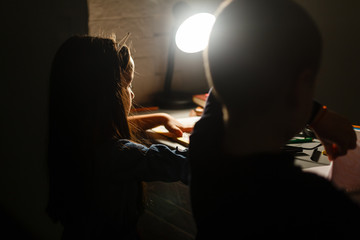 Little girl and boy doing homework in evening at home