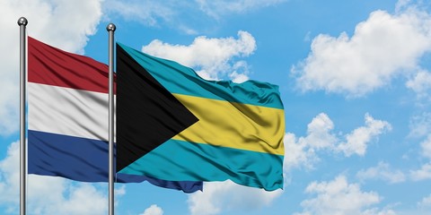 Netherlands and Bahamas flag waving in the wind against white cloudy blue sky together. Diplomacy concept, international relations.