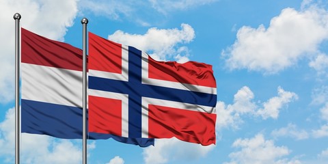 Netherlands and Bouvet Islands flag waving in the wind against white cloudy blue sky together. Diplomacy concept, international relations.