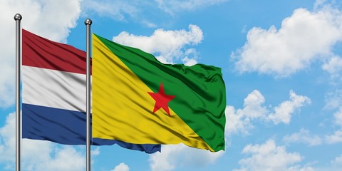 Netherlands and French Guiana flag waving in the wind against white cloudy blue sky together. Diplomacy concept, international relations.