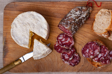 cow's milk french cheese called camembert and pork dry sausage on cutting board