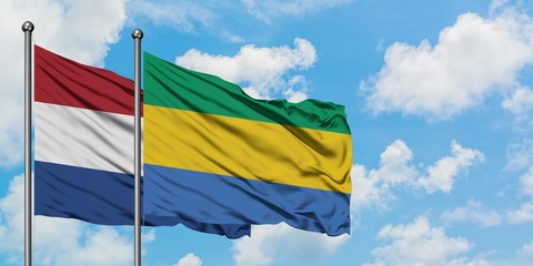 Netherlands and Gabon flag waving in the wind against white cloudy blue sky together. Diplomacy concept, international relations.