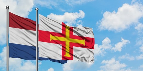 Netherlands and Guernsey flag waving in the wind against white cloudy blue sky together. Diplomacy concept, international relations.