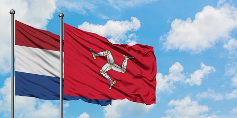 Netherlands and Isle Of Man flag waving in the wind against white cloudy blue sky together. Diplomacy concept, international relations.