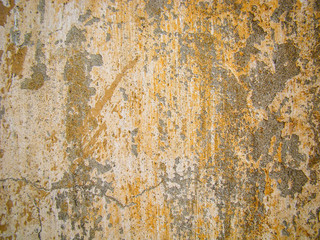 Old concrete wall. Gray potholes, peeling, cracks. Yellow paint splashes.