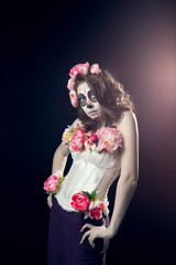 Portret of young girl with a make-up on halloween with a wreath of peonies. Her hands on hips